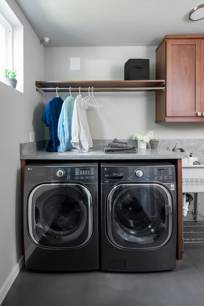 Design ideas for a small transitional single-wall dedicated laundry room in Seattle with an utility sink, shaker cabinets, medium wood cabinets, laminate benchtops, beige walls, concrete floors, a side-by-side washer and dryer, grey floor and grey benchtop.