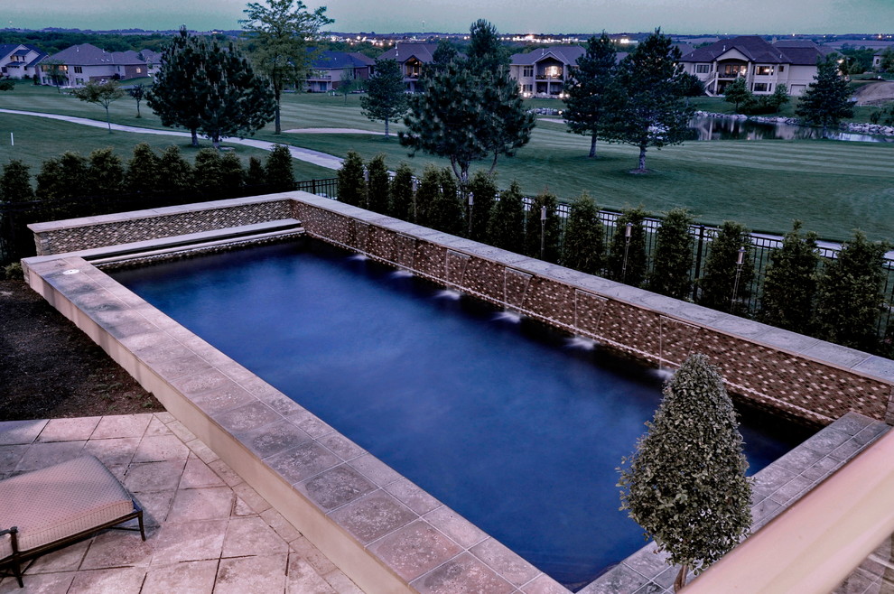 Large transitional backyard concrete paver and rectangular lap pool fountain photo in Omaha