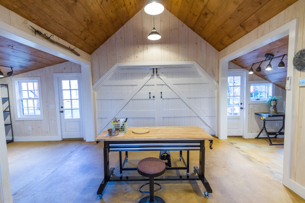 Cette image montre un bureau rustique de taille moyenne et de type studio avec un mur blanc, sol en béton ciré, aucune cheminée, un bureau indépendant, poutres apparentes et du lambris de bois.