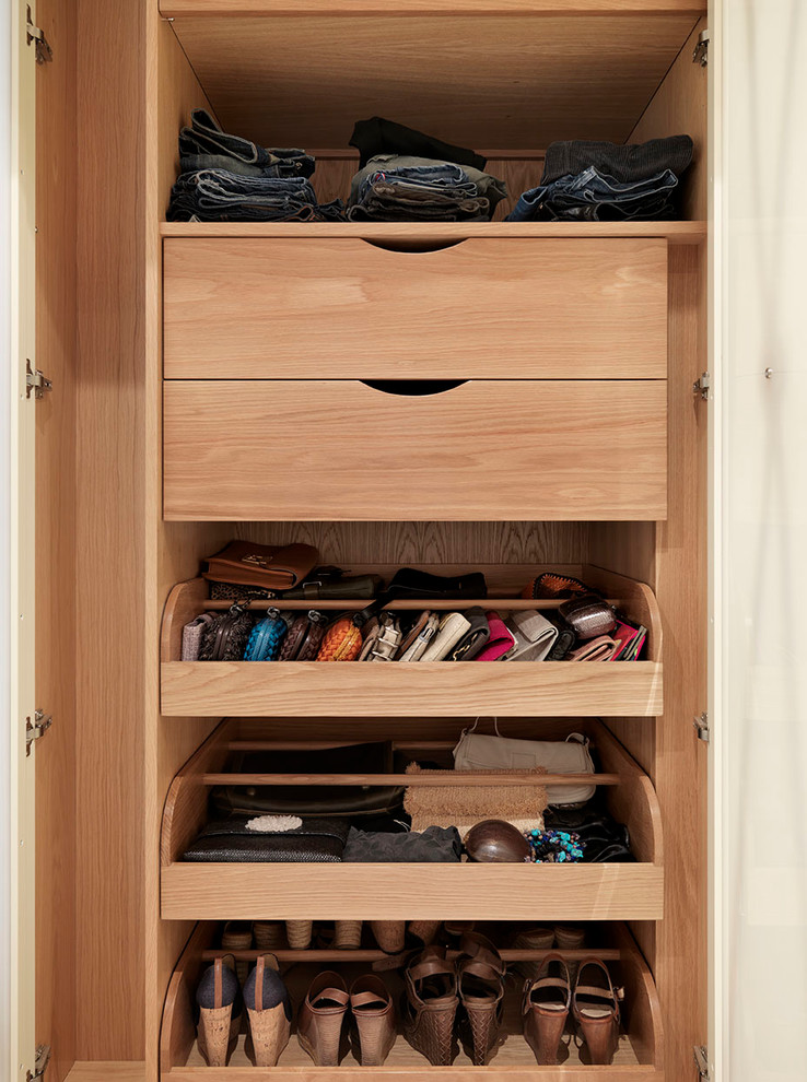 Photo of a mid-sized traditional women's walk-in wardrobe in London with open cabinets, light wood cabinets and carpet.