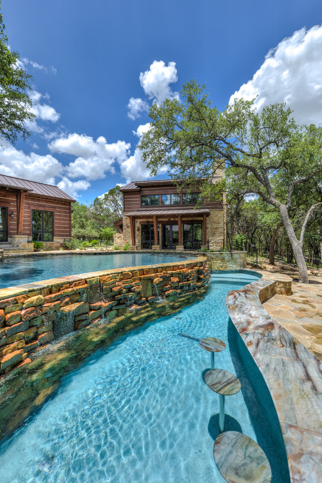 Photo of a large country backyard custom-shaped infinity pool in Austin with a hot tub and natural stone pavers.