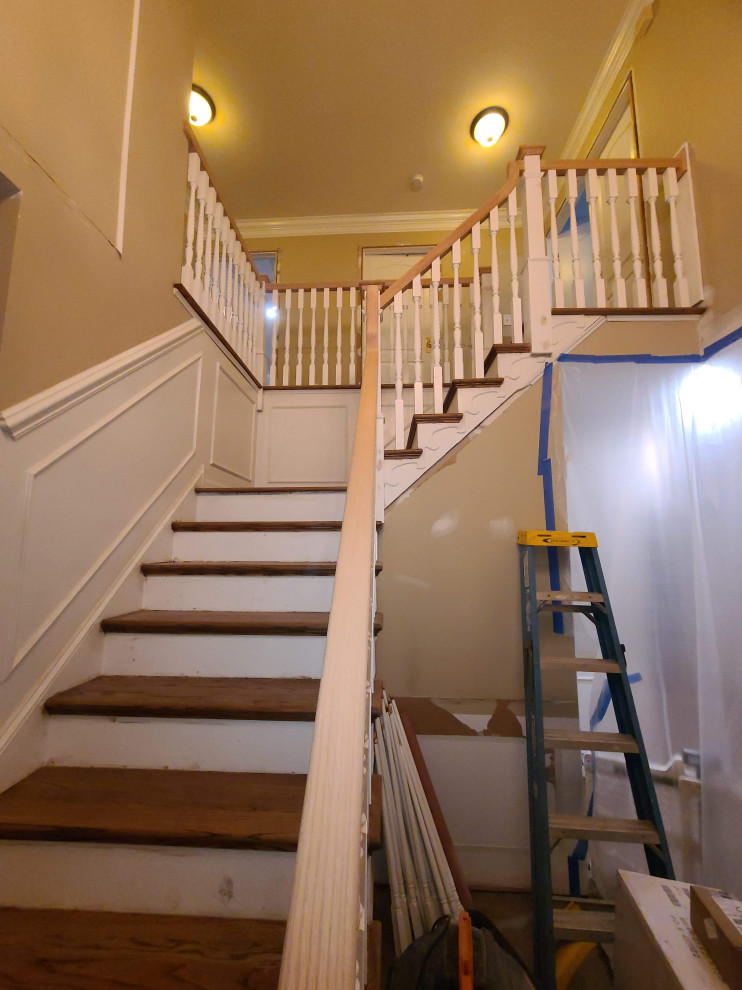 Photo of a large traditional wood l-shaped staircase in New York with travertine risers and wood railing.