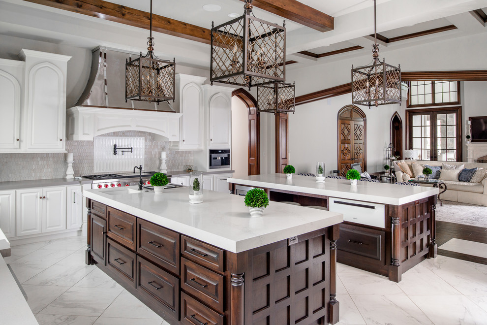 Design ideas for a large mediterranean u-shaped open plan kitchen in Houston with an undermount sink, raised-panel cabinets, white cabinets, grey splashback, stainless steel appliances, multiple islands and white floor.