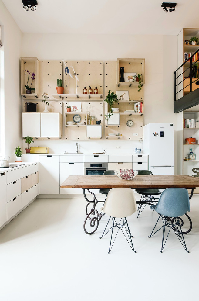 Свежая идея для дизайна: угловая кухня-гостиная в скандинавском стиле с плоскими фасадами, белыми фасадами, белым фартуком и техникой из нержавеющей стали без острова - отличное фото интерьера