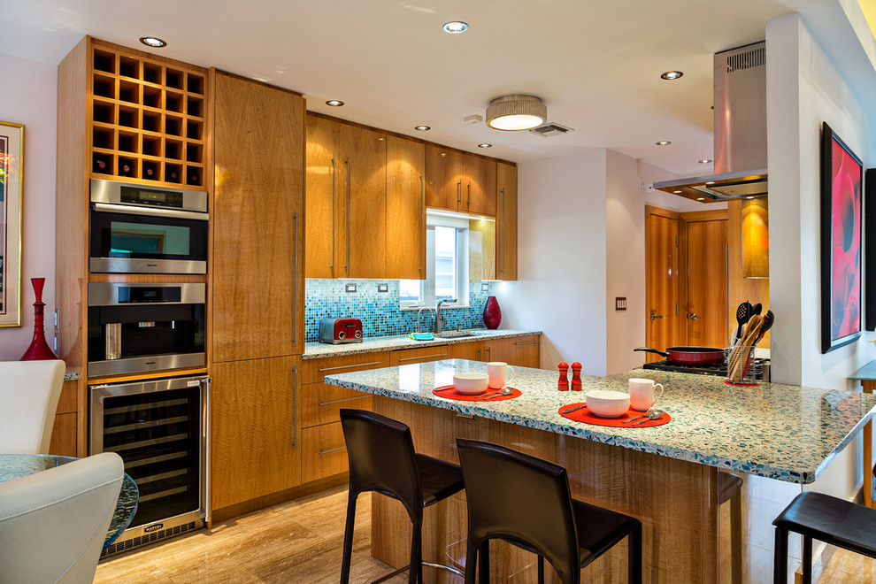 Photo of a large contemporary galley eat-in kitchen in Miami with flat-panel cabinets, medium wood cabinets, recycled glass benchtops, multi-coloured splashback, mosaic tile splashback, stainless steel appliances, medium hardwood floors and a peninsula.