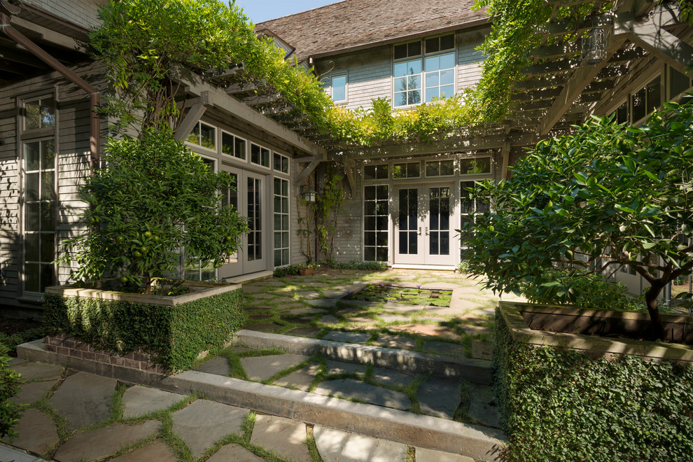 Photo of a large arts and crafts courtyard patio in Houston with a water feature, natural stone pavers and an awning.