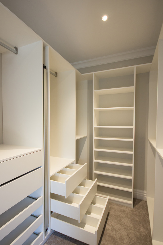 Design ideas for a mid-sized modern gender-neutral walk-in wardrobe in Wellington with white cabinets.