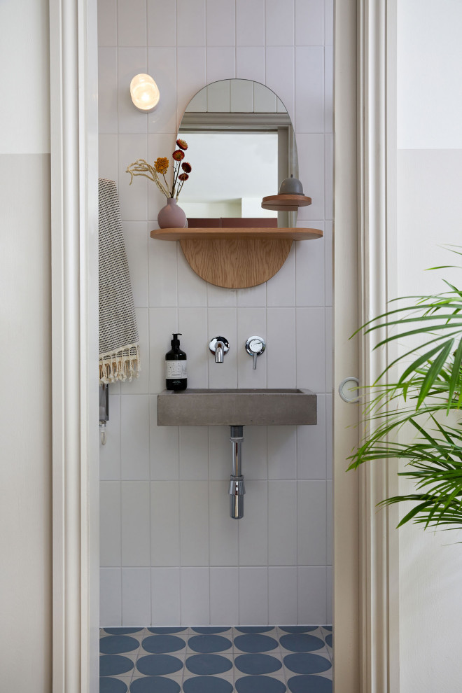 This is an example of a contemporary bathroom in Cardiff with white tiles, metro tiles, white walls, a console sink, blue floors and a single sink.