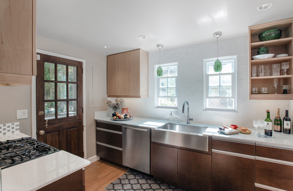 Small modern l-shaped separate kitchen in DC Metro with a farmhouse sink, flat-panel cabinets, light wood cabinets, quartz benchtops, white splashback, ceramic splashback, stainless steel appliances and light hardwood floors.