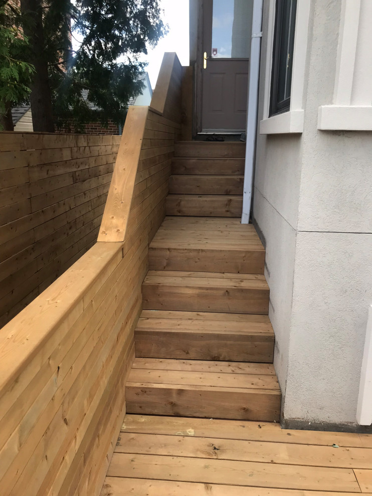 Example of a large backyard ground level wood railing deck design in Toronto