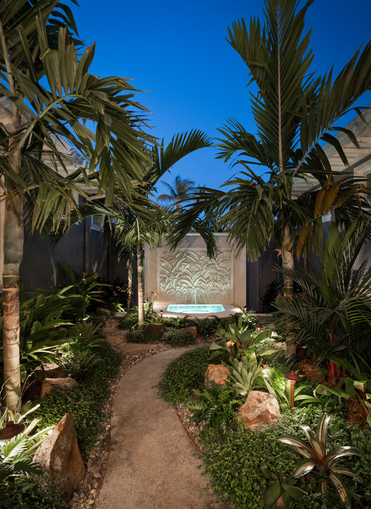 This is an example of a tropical partial sun garden in Miami with a water feature.