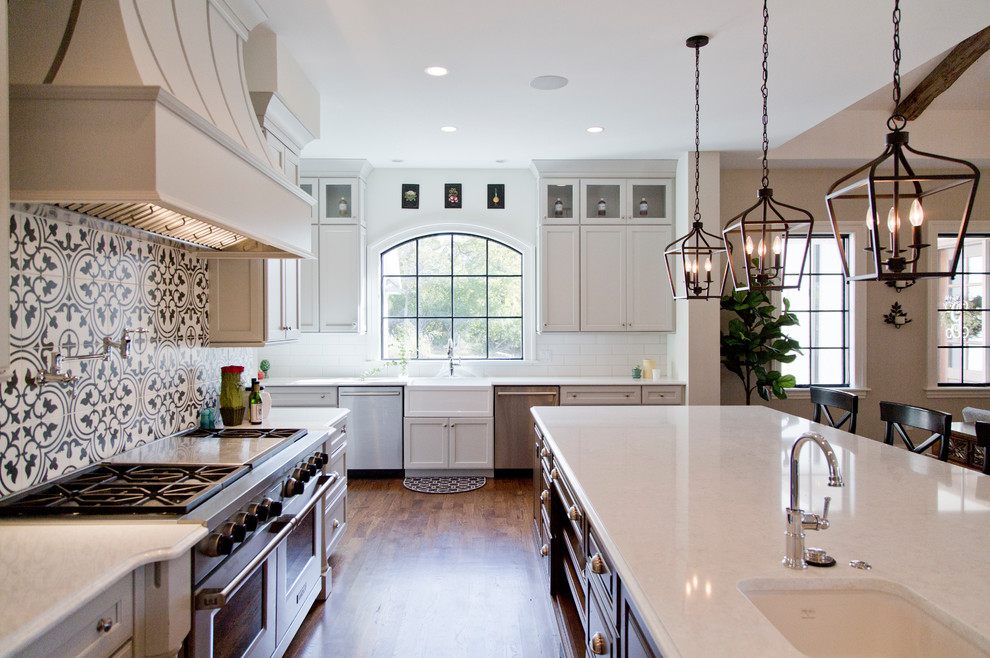 Photo of a large transitional l-shaped open plan kitchen in St Louis with multi-coloured splashback, stainless steel appliances, dark hardwood floors, brown floor, white benchtop, a farmhouse sink, recessed-panel cabinets, grey cabinets, quartz benchtops, ceramic splashback and with island.
