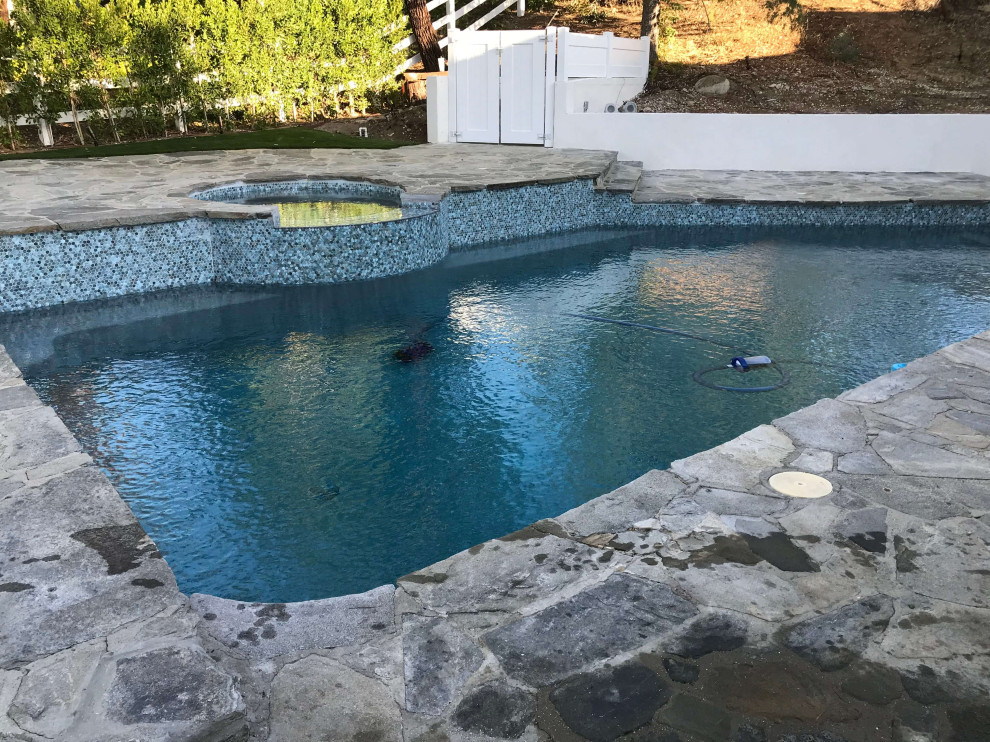 Inspiration for a mid-sized backyard stone and custom-shaped natural hot tub remodel