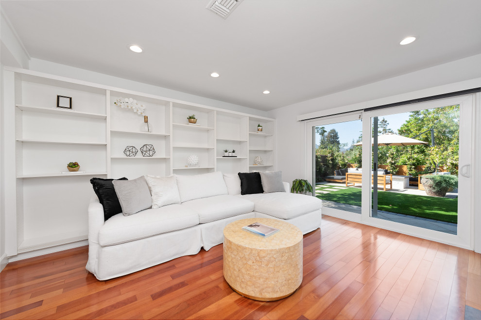 Large transitional formal open concept living room in Los Angeles with white walls, medium hardwood floors, a two-sided fireplace, a concrete fireplace surround, a wall-mounted tv, brown floor and timber.