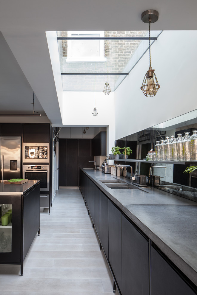 Inspiration for a contemporary u-shaped kitchen in London with an undermount sink, flat-panel cabinets, black cabinets, concrete benchtops, metallic splashback, mirror splashback, stainless steel appliances, light hardwood floors, with island, beige floor and grey benchtop.