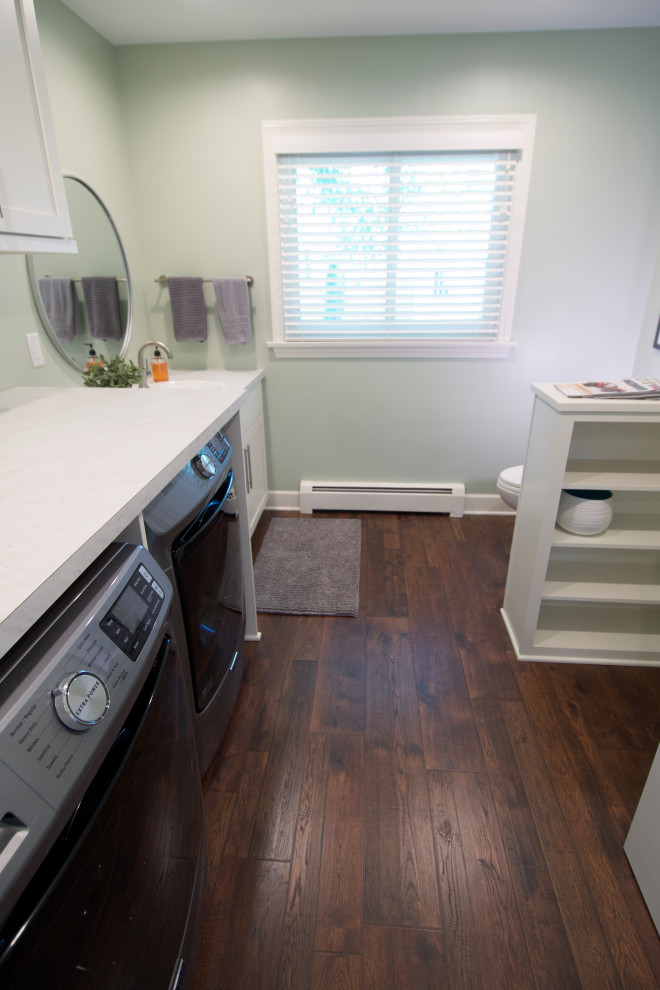 Foto di una piccola sala lavanderia classica con ante in stile shaker, ante bianche, top in laminato, pareti verdi, pavimento in laminato, lavatrice e asciugatrice affiancate, pavimento marrone e top bianco