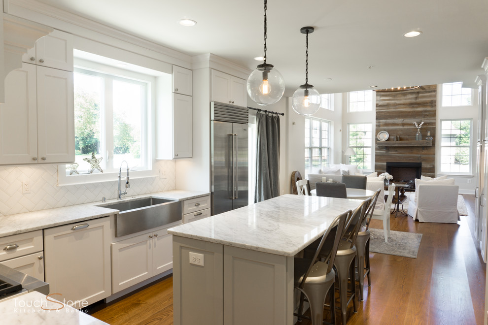 Inspiration for a mid-sized transitional l-shaped eat-in kitchen in Philadelphia with a farmhouse sink, recessed-panel cabinets, white cabinets, granite benchtops, white splashback, glass tile splashback, stainless steel appliances, dark hardwood floors, with island and brown floor.