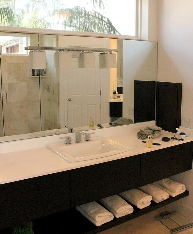 This is an example of a mid-sized traditional master bathroom in Tampa with a corner shower, white walls, a drop-in sink, a hinged shower door, a drop-in tub, solid surface benchtops, open cabinets, black cabinets, a two-piece toilet, beige tile, ceramic floors and beige floor.