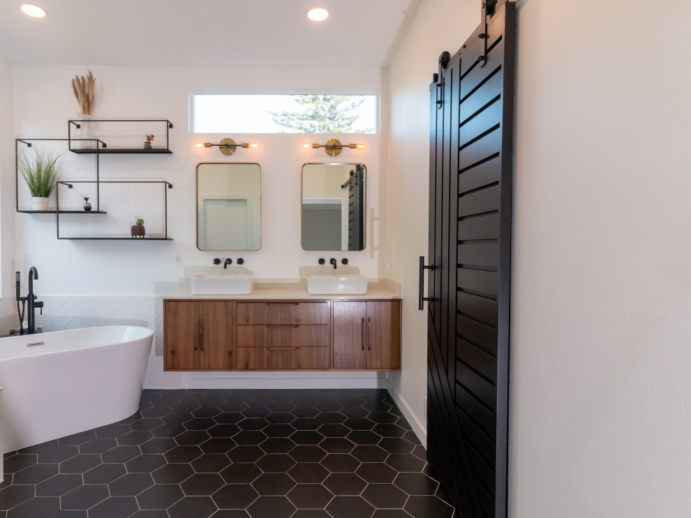 Inspiration for a midcentury bathroom in Orange County with flat-panel cabinets, brown cabinets, a freestanding tub, a corner shower, black and white tile, porcelain tile, white walls, porcelain floors, a vessel sink, engineered quartz benchtops, black floor, a hinged shower door, white benchtops, a shower seat, a double vanity and a floating vanity.