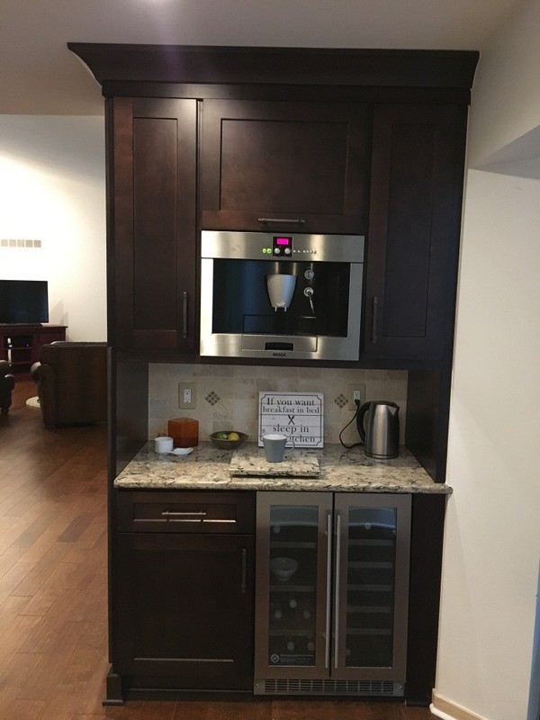 Large transitional u-shaped porcelain tile home design photo in Detroit with a farmhouse sink, shaker cabinets, white cabinets, quartz countertops, beige backsplash, stone tile backsplash, stainless steel appliances and an island