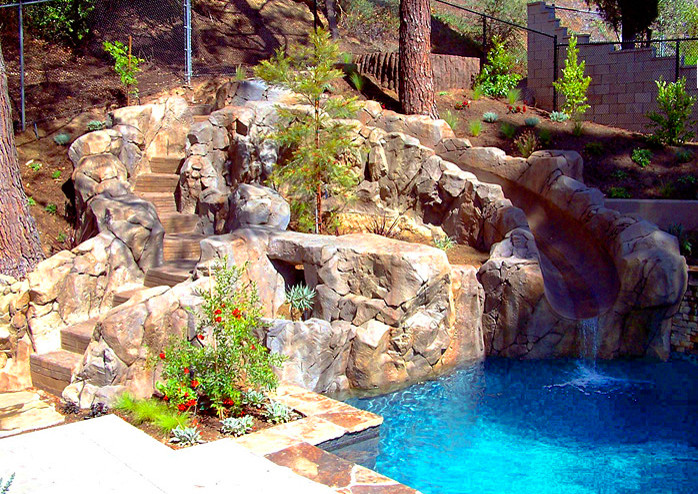 Photo of a small country backyard natural pool in Orange County with a water feature.
