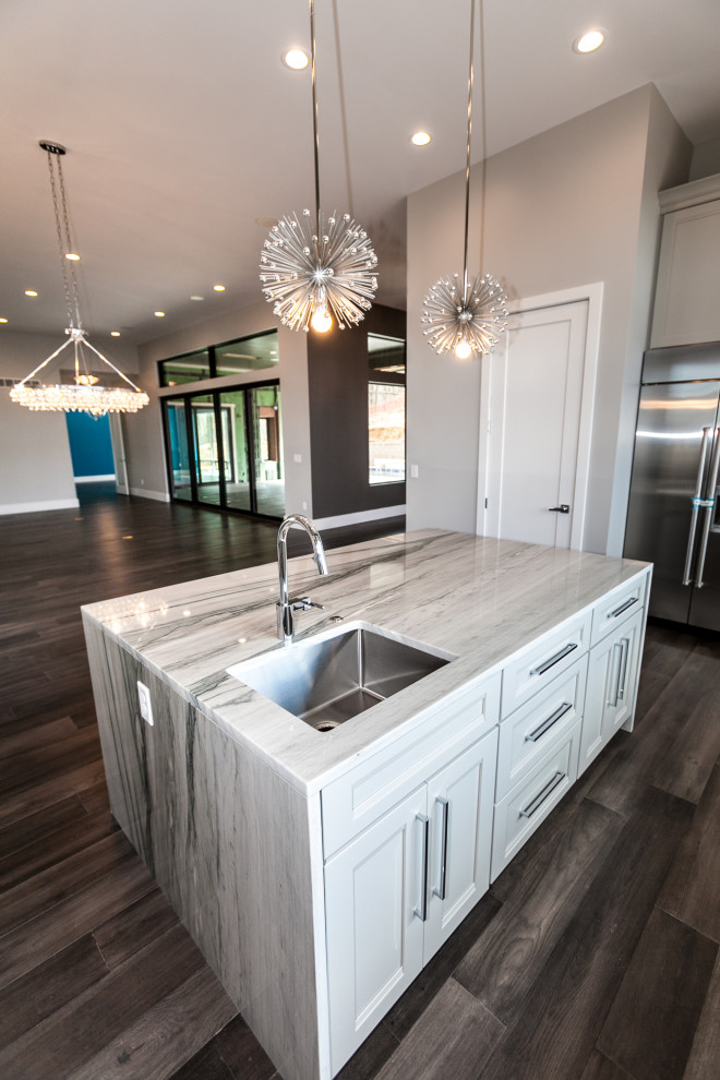 This is an example of a midcentury u-shaped eat-in kitchen in Salt Lake City with an undermount sink, shaker cabinets, white cabinets, marble benchtops, blue splashback, glass tile splashback, stainless steel appliances, dark hardwood floors, with island, brown floor and black benchtop.