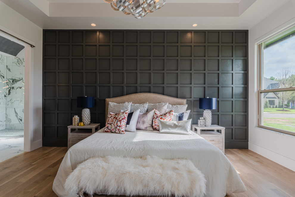 Large modern master bedroom in Oklahoma City with white walls, light hardwood floors, coffered and wood walls.
