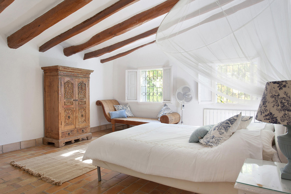 Large country master bedroom in Florence with white walls and brick floors.