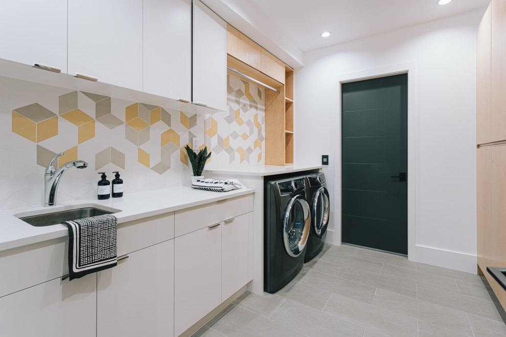 This is an example of a mid-sized modern galley utility room in Vancouver with a drop-in sink, flat-panel cabinets, white cabinets, granite benchtops, white walls, porcelain floors, a concealed washer and dryer, beige floor and white benchtop.