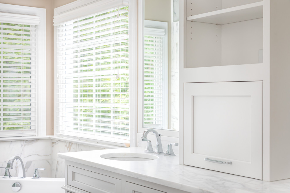 Freestanding bathtub - mid-sized transitional master white tile and marble tile dark wood floor and brown floor freestanding bathtub idea in Raleigh with recessed-panel cabinets, white cabinets, beige walls, an undermount sink, marble countertops, a hinged shower door and white countertops