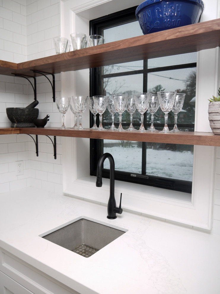 Inspiration for a mid-sized transitional l-shaped porcelain tile and gray floor enclosed kitchen remodel in Toronto with a farmhouse sink, recessed-panel cabinets, white cabinets, quartz countertops, white backsplash, porcelain backsplash, stainless steel appliances, an island and white countertops