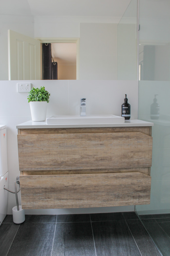 Small 3/4 bathroom in Perth with flat-panel cabinets, light wood cabinets, an open shower, a one-piece toilet, white tile, ceramic tile, white walls, porcelain floors, a vessel sink, engineered quartz benchtops, black floor and white benchtops.
