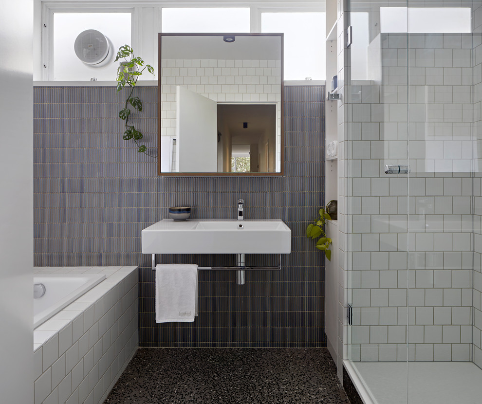 Small contemporary master bathroom in Melbourne with a drop-in tub, ceramic tile, grey walls, a wall-mount sink, a hinged shower door, an alcove shower, gray tile, white tile, grey floor, white benchtops and concrete floors.