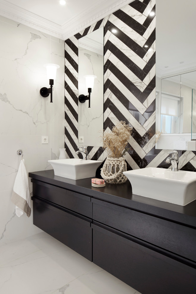Inspiration for a contemporary bathroom in Other with flat-panel cabinets, black cabinets, black and white tile, white walls, a vessel sink, wood benchtops and white floor.