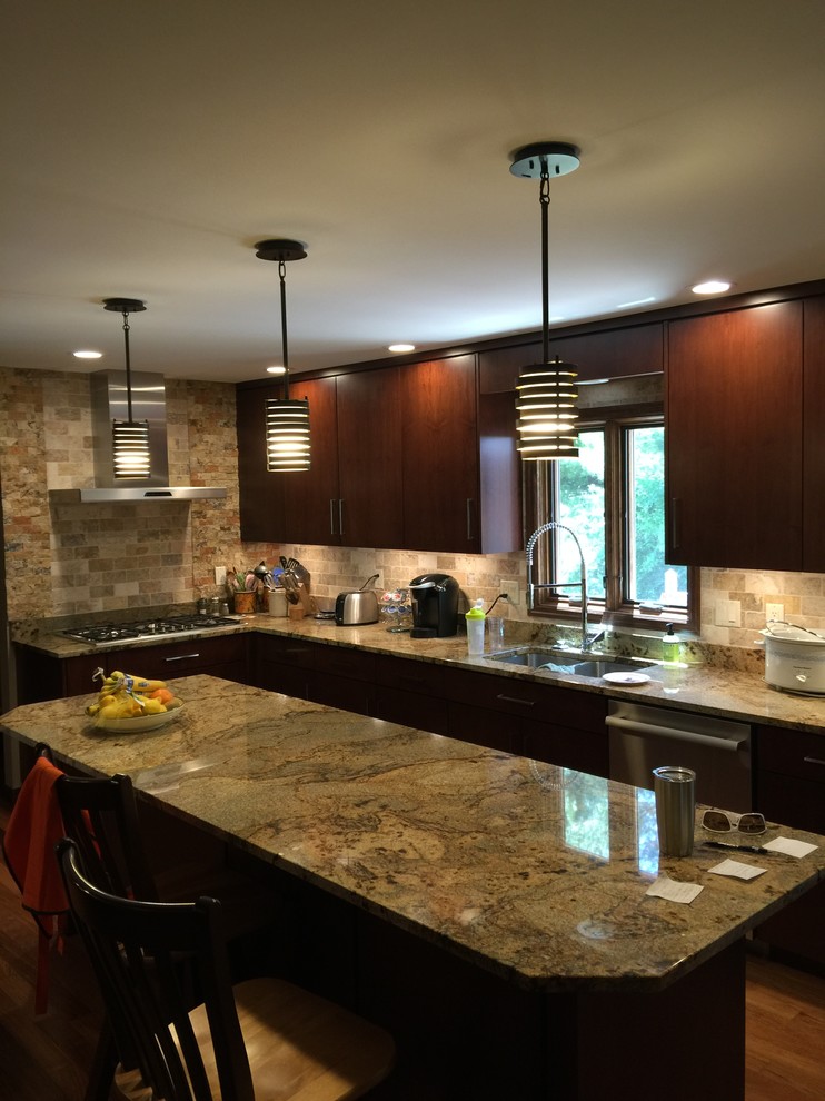 Large transitional u-shaped medium tone wood floor eat-in kitchen photo in Chicago with an undermount sink, flat-panel cabinets, dark wood cabinets, granite countertops, beige backsplash, stone tile backsplash, stainless steel appliances and an island