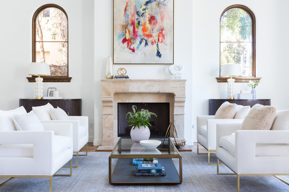 Inspiration for a large mediterranean formal open concept living room in Los Angeles with white walls, medium hardwood floors, a standard fireplace, a concrete fireplace surround and no tv.