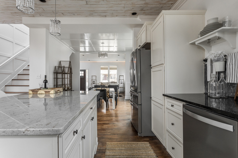 Inspiration for a small transitional l-shaped eat-in kitchen in Indianapolis with an undermount sink, recessed-panel cabinets, white cabinets, granite benchtops, black splashback, slate splashback, stainless steel appliances, medium hardwood floors, with island, brown floor and black benchtop.