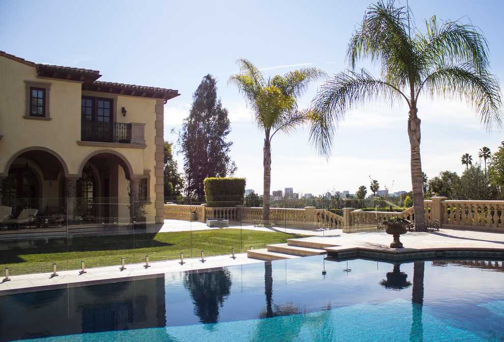 This is an example of a large mediterranean backyard custom-shaped pool in Los Angeles with a hot tub and concrete pavers.