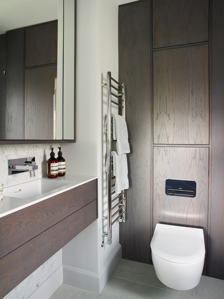 This is an example of a small contemporary master bathroom in Surrey with flat-panel cabinets, dark wood cabinets, an open shower, a wall-mount toilet, an integrated sink, marble benchtops and a hinged shower door.