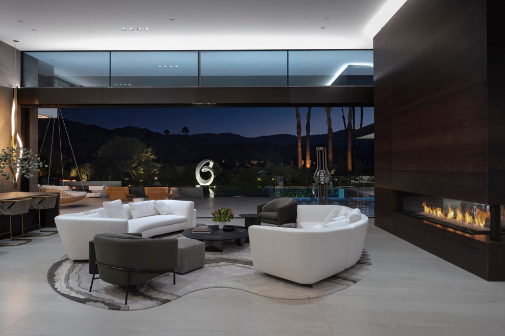 This is an example of an expansive modern formal open concept living room in Los Angeles with porcelain floors, a two-sided fireplace, a wood fireplace surround, white floor and recessed.