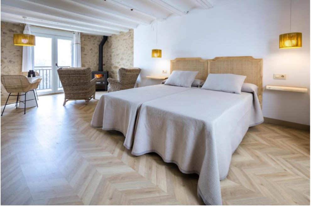 他の地域にある巨大な北欧スタイルのおしゃれなロフト寝室 (白い壁、淡色無垢フローリング、薪ストーブ、表し梁、羽目板の壁) のインテリア