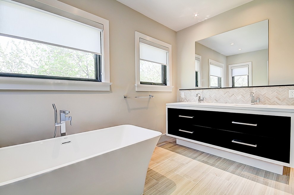 Design ideas for a mid-sized contemporary master bathroom in Toronto with flat-panel cabinets, black cabinets, a freestanding tub, beige tile, stone tile, beige walls, light hardwood floors, an undermount sink, engineered quartz benchtops, beige floor and white benchtops.