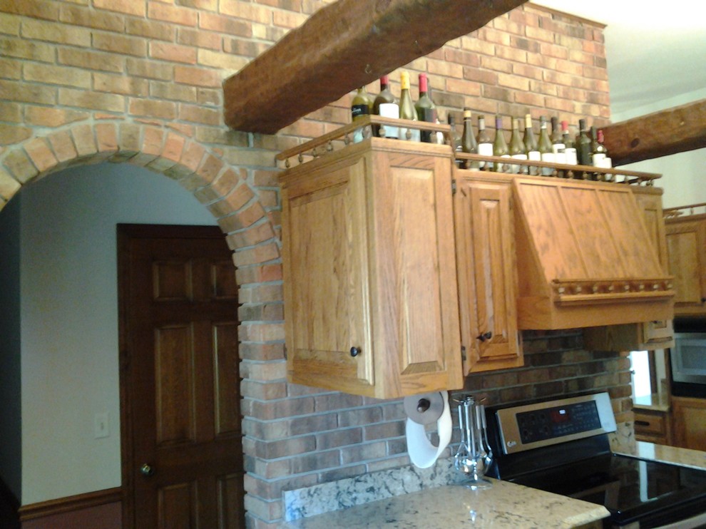 Example of a mid-sized mountain style medium tone wood floor enclosed kitchen design in Indianapolis with an undermount sink, raised-panel cabinets, medium tone wood cabinets, quartzite countertops, stainless steel appliances and no island
