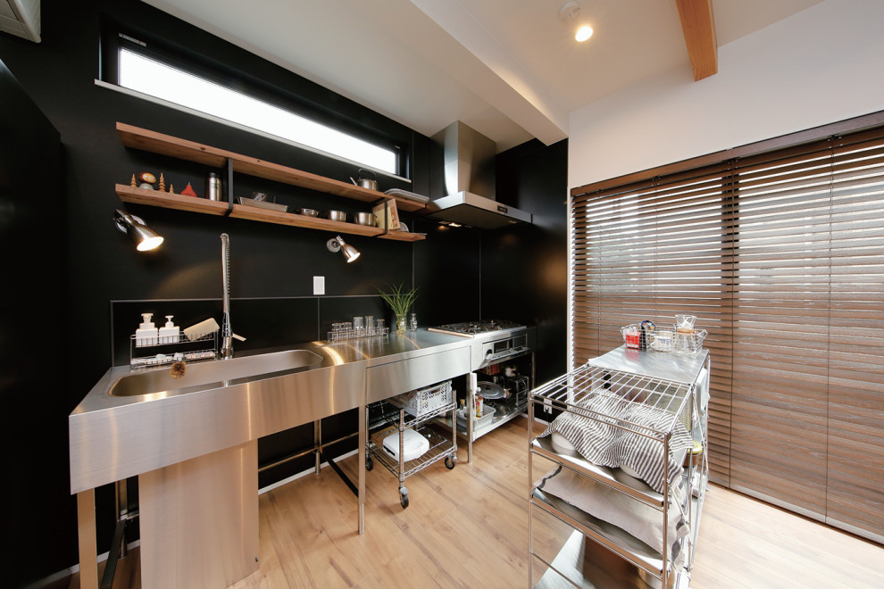 Design ideas for a mid-sized industrial single-wall open plan kitchen in Tokyo Suburbs with an integrated sink, open cabinets, stainless steel cabinets, stainless steel benchtops, black splashback, ceramic splashback, medium hardwood floors, brown floor and grey benchtop.
