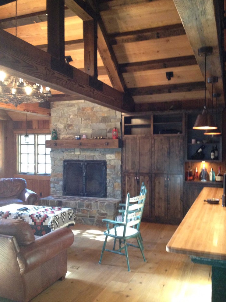 Photo of a mid-sized country open concept family room in Other with light hardwood floors, a standard fireplace, a stone fireplace surround and brown walls.