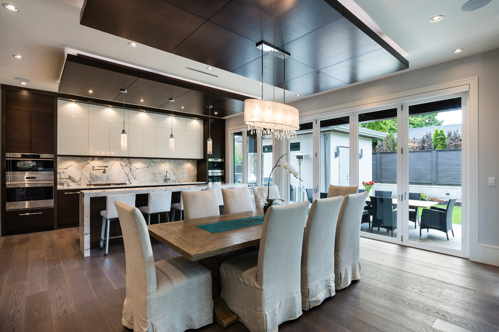Design ideas for a large contemporary l-shaped open plan kitchen in Vancouver with an undermount sink, flat-panel cabinets, marble benchtops, white splashback, marble splashback, stainless steel appliances, medium hardwood floors, with island and brown floor.
