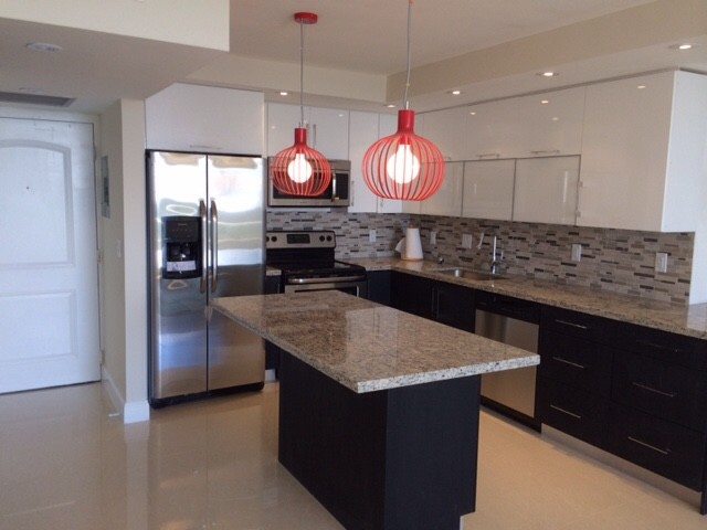 Modern kitchen with red pendants over the island. Granite counter tops and mosai