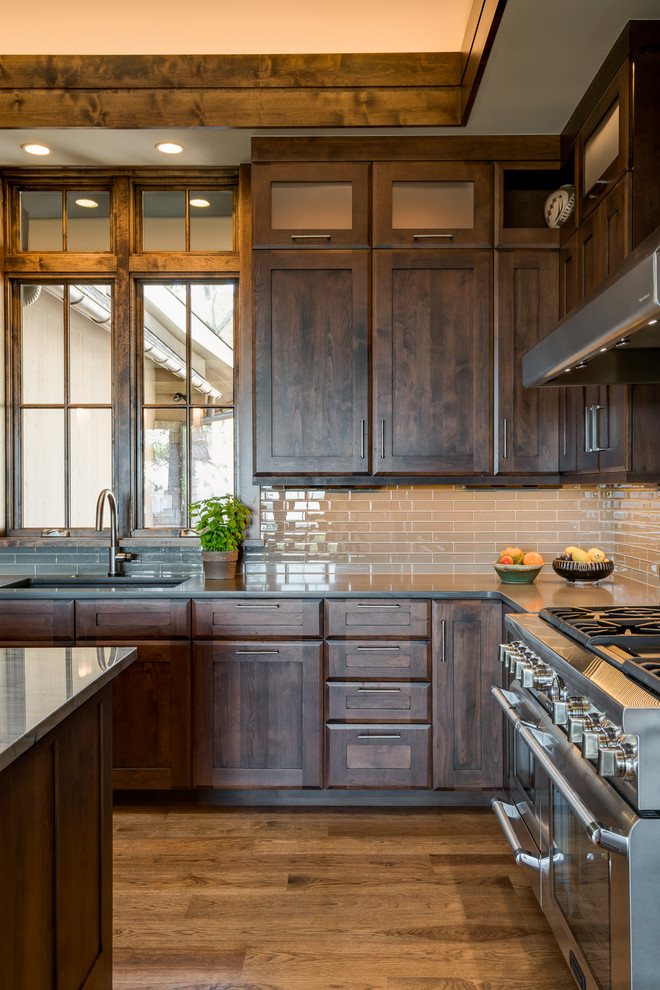 Large transitional u-shaped medium tone wood floor eat-in kitchen photo with an undermount sink, shaker cabinets, dark wood cabinets, quartz countertops, gray backsplash, glass tile backsplash, stainless steel appliances and an island