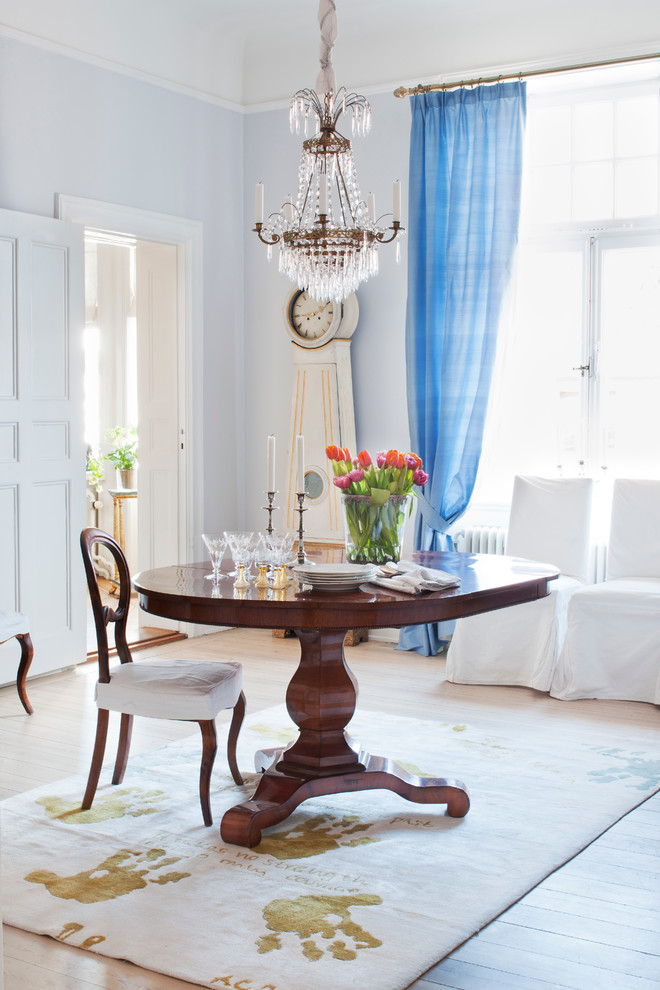 This is an example of a small traditional separate dining room in Stockholm with blue walls, light hardwood floors and no fireplace.