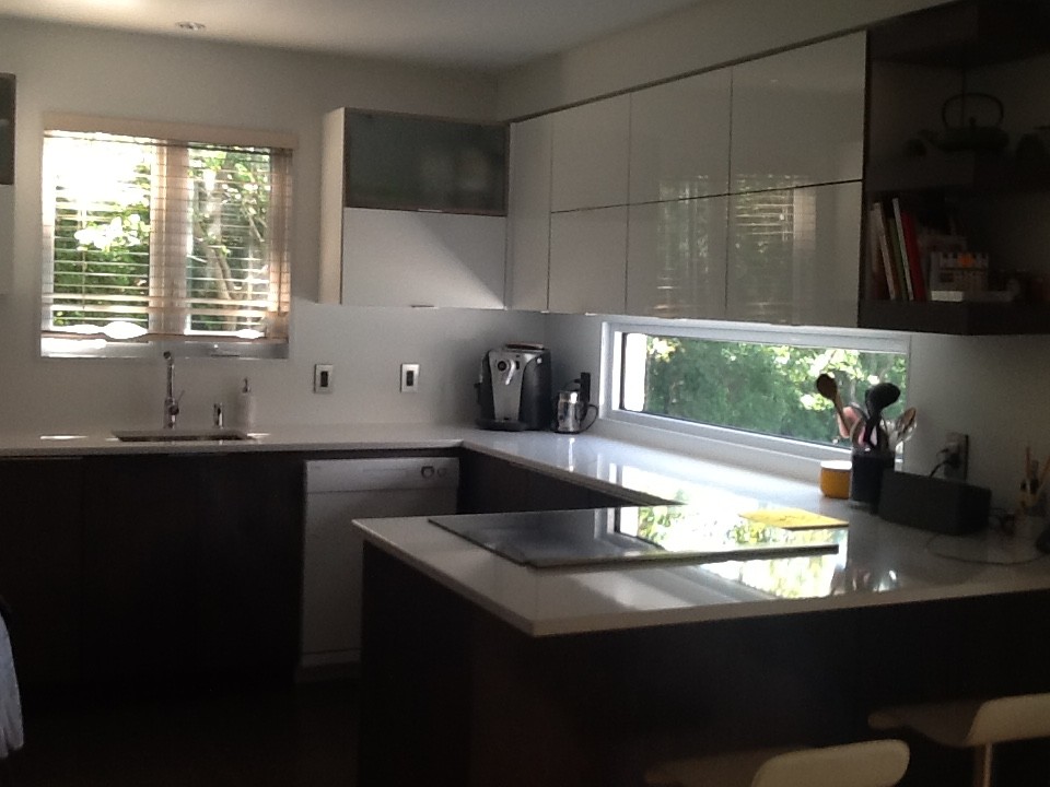 Photo of a mid-sized contemporary u-shaped eat-in kitchen in Montreal with flat-panel cabinets, white cabinets, stainless steel appliances and a peninsula.